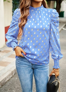 Detail showing the elegant ruffled cuffs and gold polka dot pattern on the blue blouse