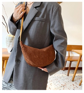 Brown corduroy crossbody bag shown on a model in a cozy cafe setting for a stylish look
