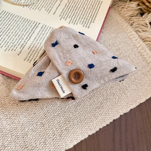 Close-up of oatmeal linen hair tie with embroidered dots and Hand Made label