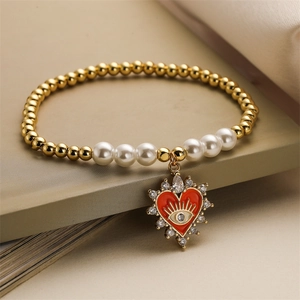 Detailed macro view of evil eye heart pendant on gold and pearl beaded bracelet