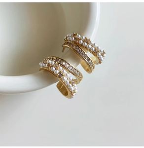 Detailed close-up of 14k gold plated C-shaped earrings with pearls and pavé set zircons
