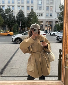 Detail of khaki belted trench coat with wide lapels and large pockets in city street setting