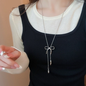 Close-up of a silver bow ballet-style pendant necklace worn by a fashion model