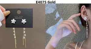 Detailed view of long gold tassel earrings with white flowers and clear cubic zirconia stones