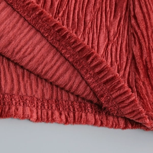 Detailed close-up of red corduroy fabric texture and fine stitching on the skirt hem