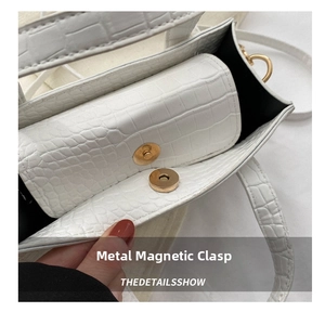 Close-up of white croc-textured handbag showing magnetic buckle and inner details