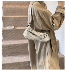 Detail of silver metallic underarm bag featuring Y2K style metal eyelets and wide strap