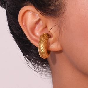 Detail of 18K gold-plated C-shaped ear cuff with fish scale texture on model's ear