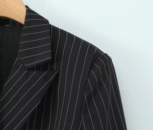 Détail du revers et de l'épaule d'un blazer noir à fines rayures blanches verticales