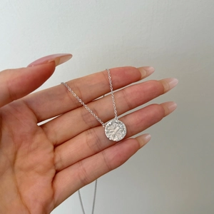 Detail of S925 sterling silver disk pendant with hammered texture and small zircon stones