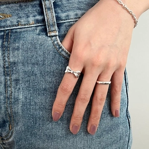 925 silver bow ring and minimalist band on model hand with blue denim background