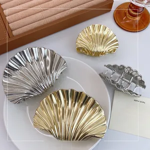 Detail showing polished gold and silver scallop shell metal hair claws on a jewelry tray