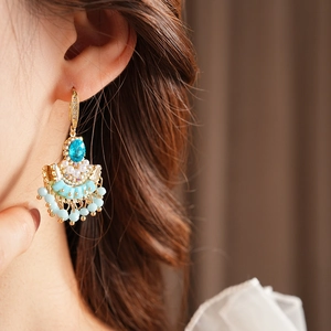 Gros plan de boucles d'oreilles vintage en éventail avec zircon bleu et pompons