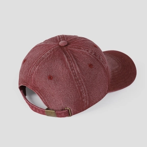 Detail view of washed burgundy denim baseball cap featuring an adjustable metal buckle strap