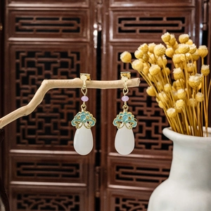 Detail of vintage beaded tassel earrings with white teardrop pearls on a rustic wood branch