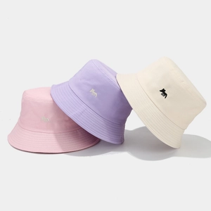 Three minimalist cotton bucket hats with fox embroidery in pink, purple, and beige
