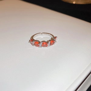 Close-up of adjustable silver ring with five round orange stones and cubic zirconia