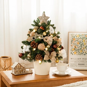 Mini lighted Christmas tree with pine cones and gold ornaments on a cozy wooden table
