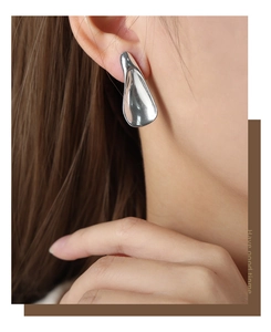 Detail of silver waterdrop earring in polished stainless steel on model ear