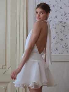 Detail of white halter neck backless dress with long ties and tiered ruffle skirt hem