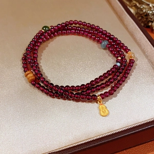 Detailed view of garnet multi-wrap beaded bracelet with a golden gourd pendant