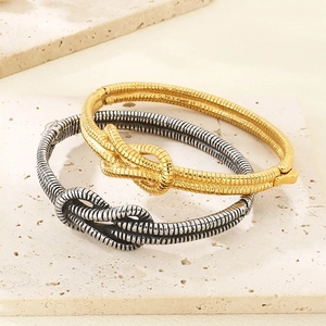 Detailed view of knot-style gold and silver textured bangles on a stone base