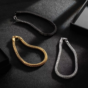 Three men's woven titanium steel bracelets in black, gold, and silver on a dark background