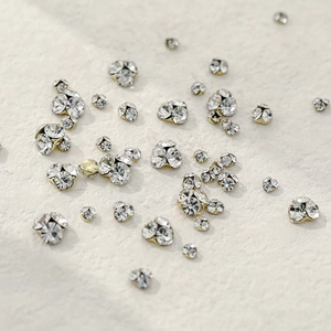 Strass en cristal brillant pour nail art avec base dorée sur une surface texturée blanche