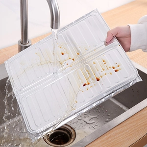 Aluminum foil oil splash guard being rinsed under kitchen tap to show easy cleaning