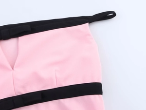 Primo piano del tessuto rosa con profili neri e dettaglio fiocco sul top elegante