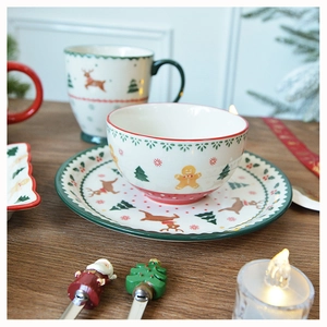 Festive Christmas ceramic tableware set with reindeer and gingerbread man on wooden table