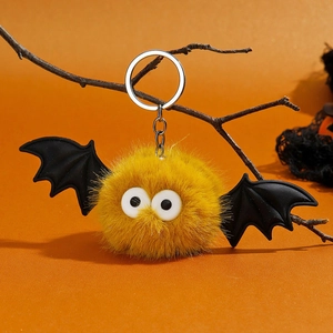 Détail d'un porte-clés chauve-souris en peluche jaune avec des ailes noires et un anneau