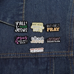 Christian enamel lapel pins with religious quotes pinned on a blue denim jacket pocket