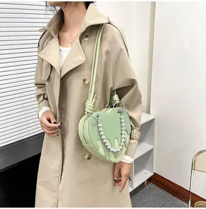 Detail of light green heart bag with white drip design and silver bead chain strap