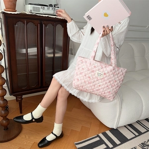 Close-up of pink quilted floral tote bag held by a model in a vintage aesthetic setting