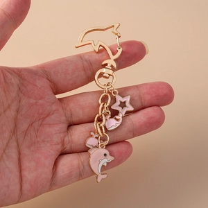 Handheld photo of a creative pink dolphin and star keychain with a gold chain and clasp