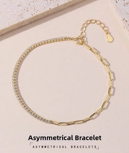 Detail of asymmetric gold bracelet with shimmering tennis chain and paperclip links