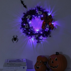 Detail of Halloween wreath with purple LED lights, white ghosts, and orange bows on wall