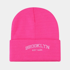 Close-up of pink knit beanie with white Brooklyn embroidery and ribbed texture