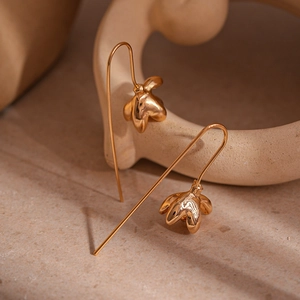 Détail macro de boucles d'oreilles fleur dorée à trois pétales avec finition miroir poli