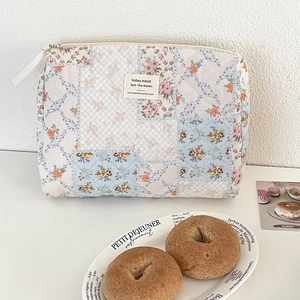 Detailed close-up of quilted floral patchwork toiletry bag with soft fabric and zipper