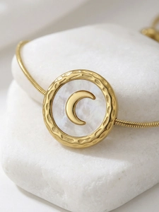 Detailed macro view of the gold hammered texture pendant with white shell and crescent moon