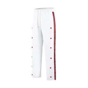 Detail of white trousers featuring red-green plaid side stripes and red button accents
