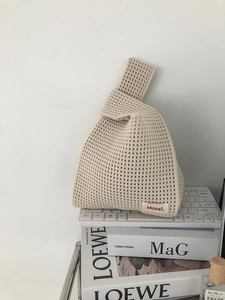 Detail of beige knitted knot bag showing openwork mesh texture and brand woven label