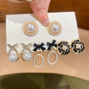 Detailed view of four pairs of vintage pearl and camellia earrings in hand