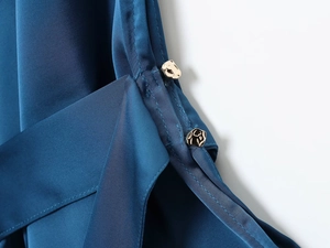 Detailed macro view of dark blue satin fabric and geometric gold metal button detail