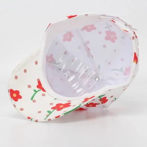 Close-up of white floral baseball cap showing red flowers, stitching, and inner lining