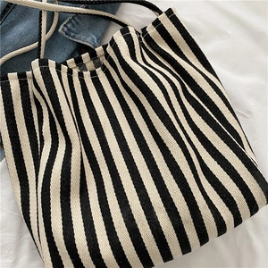 Classic black and white striped canvas tote bag with woven handles on white fabric