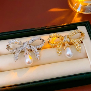 Détail de broches nœud papillon en perles dorées et argentées avec incrustation zircon