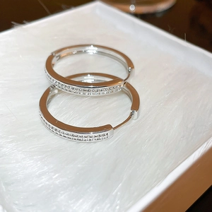 Macro shot of silver geometric hoop earrings with pave cubic zirconia on soft white fur